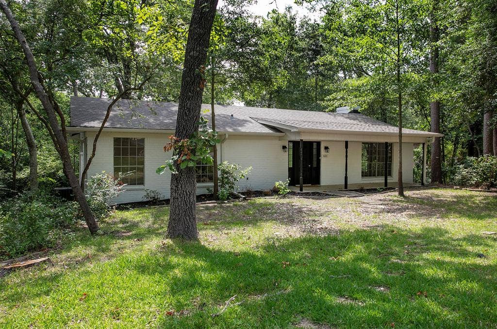 431 Lone Star Lane, Hideaway, TX 75771 Painted brick exterior featuring a covered front porch, multi-pane windows, and a mature tree-lined lot