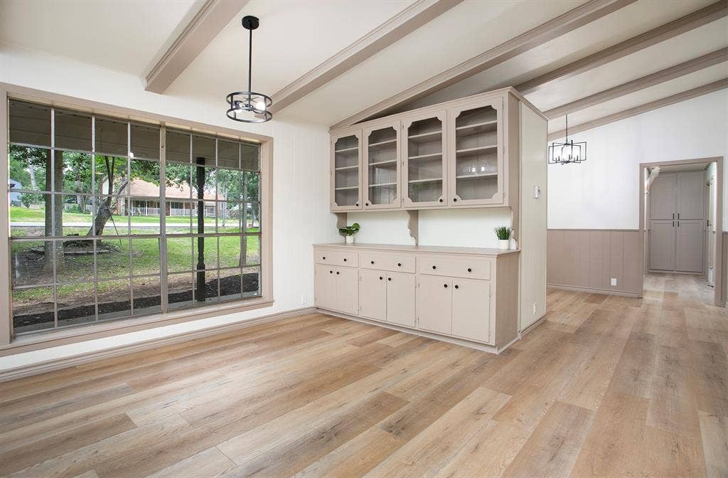 431 Lone Star Lane, Hideaway, TX 75771 Large grid-pattern window, built-in cabinetry with glass-front display uppers, exposed ceiling beams, wood-finish flooring, and wainscoting