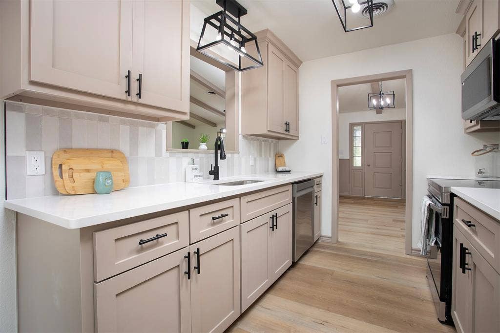 431 Lone Star Lane, Hideaway, TX 75771 Kitchen featuring soft-tone cabinetry with matte black hardware, quartz countertops, a vertical-patterned tile backsplash, and geometric cage-style light fixtures