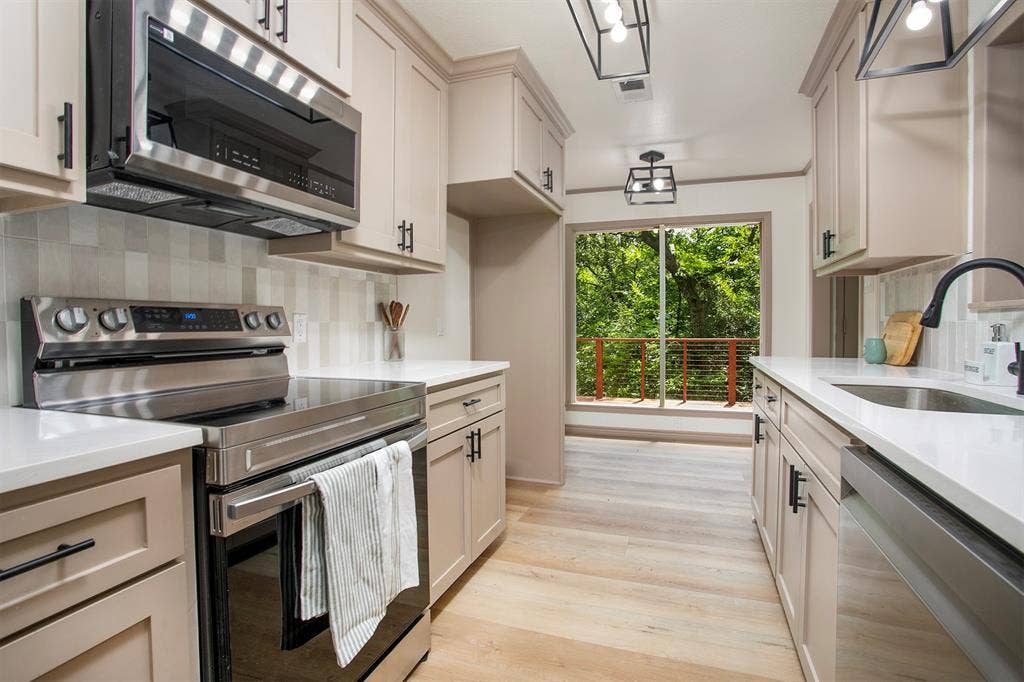 431 Lone Star Lane, Hideaway, TX 75771 Kitchen featuring neutral-toned cabinetry, light-colored countertops, stainless steel appliances, wood-finish flooring, and geometric pendant lighting