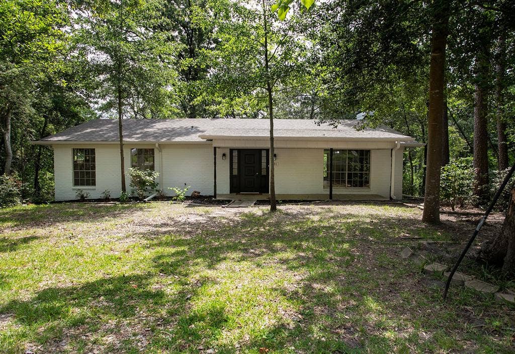 431 Lone Star Lane, Hideaway, TX 75771 Single-story residence featuring white painted brick exterior, a covered front porch, multi-pane windows, and a mature tree-lined lot