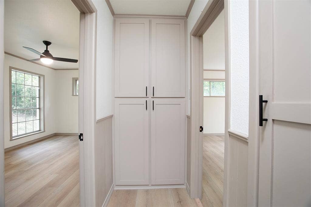 431 Lone Star Lane, Hideaway, TX 75771 Hallway featuring floor-to-ceiling built-in cabinetry, wood-finish flooring, and shaker-style doors with matte black hardware