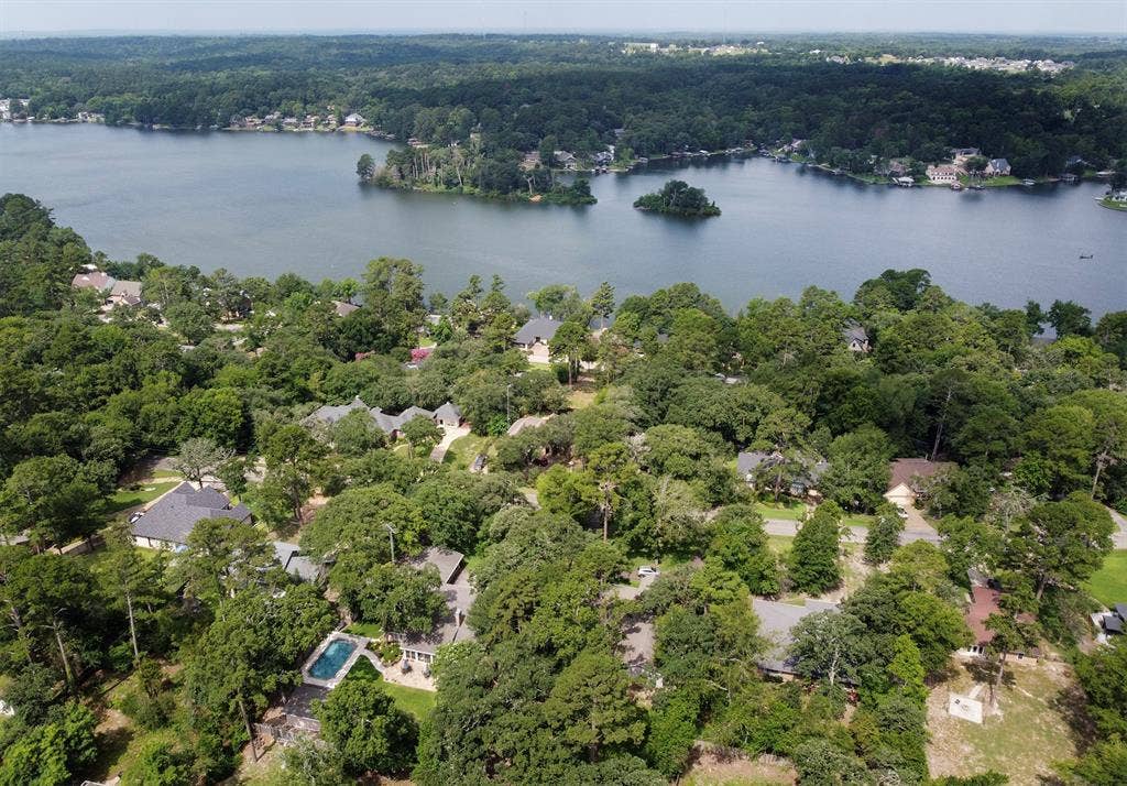 431 Lone Star Lane, Hideaway, TX 75771 Aerial perspective featuring a residential lot with a private rectangular swimming pool, dense perimeter tree canopy, and direct proximity to a large inland lake