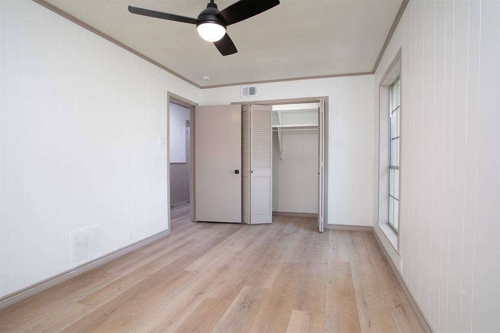 431 Lone Star Lane, Hideaway, TX 75771 Room featuring vertical wall paneling, wood-finish flooring, a ceiling fan with integrated lighting, and a closet with bifold louvered doors