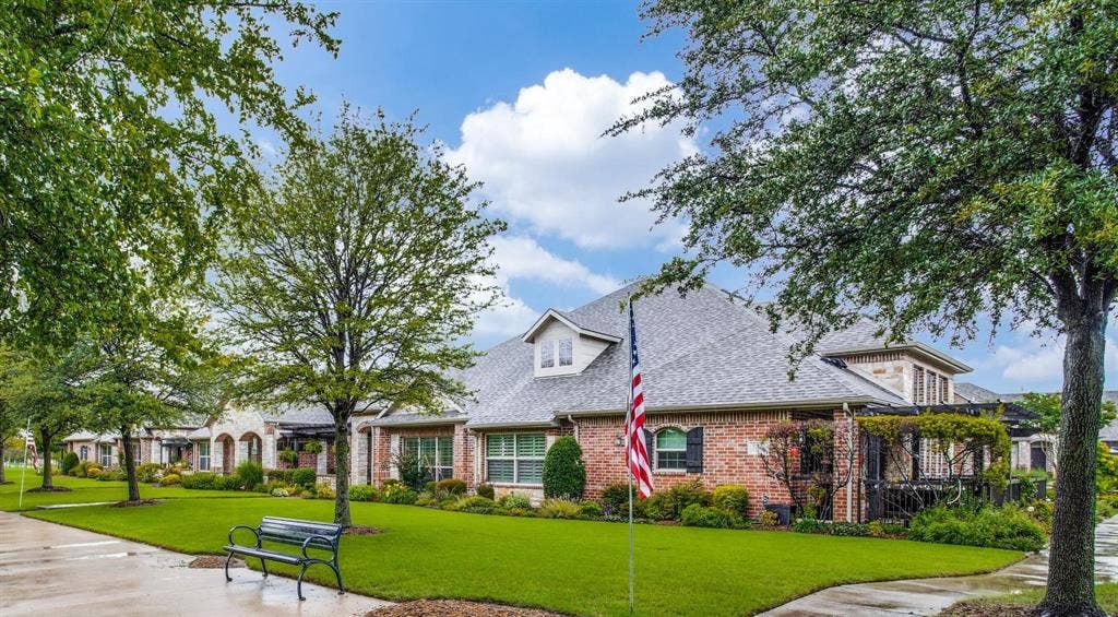 Brick exterior with stone accents, architectural shingle roof, dormer window, and mature landscaping