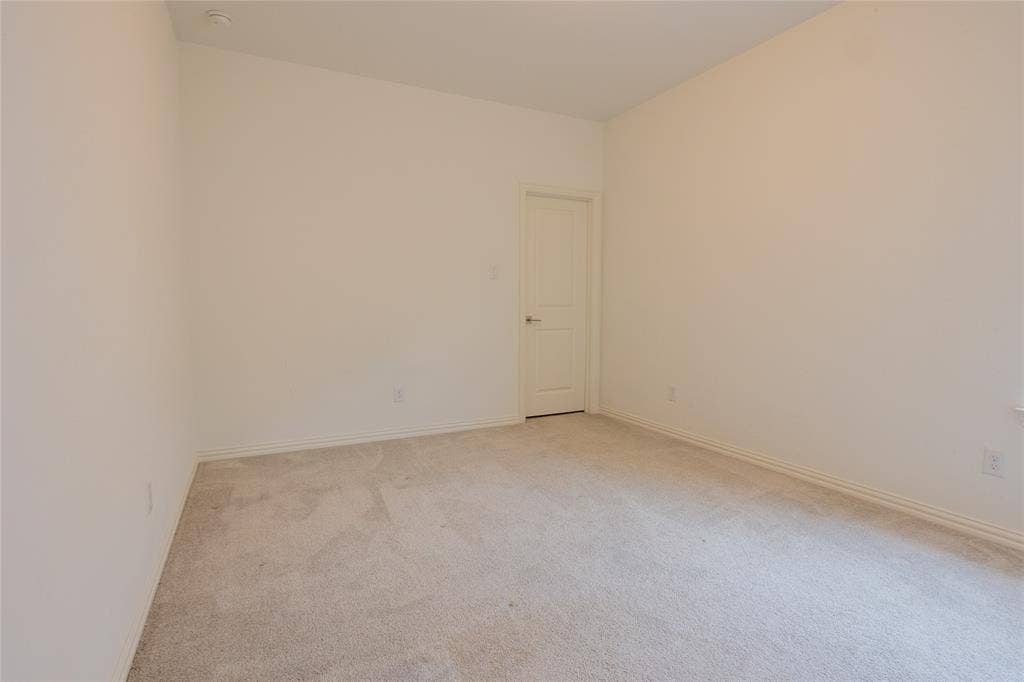 Neutral-toned wall finish, high ceilings, and plush wall-to-wall carpeting complemented by a single-panel interior door