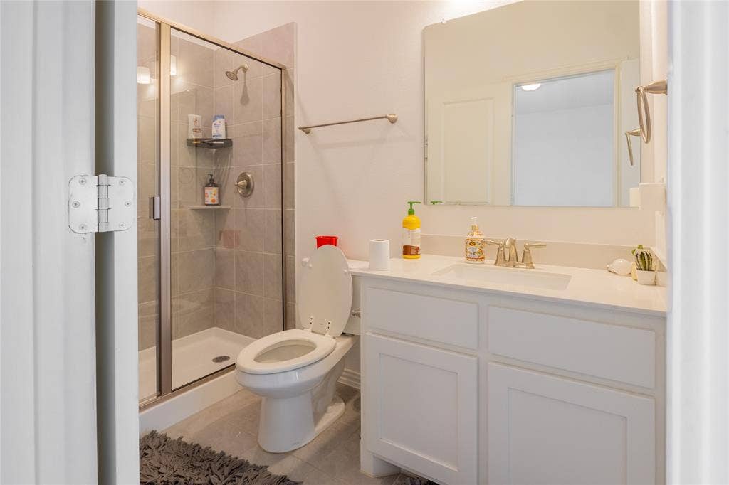 Bathroom featuring a white vanity with an integrated sink, polished metal faucet, walk-in shower with a glass enclosure, and a rectangular wall-mounted mirror