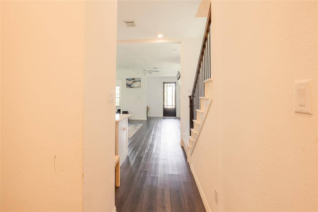 Interior space featuring dark wood-finish flooring, staircase with a dark wood handrail and vertical balusters, and a glass-paneled entry door
