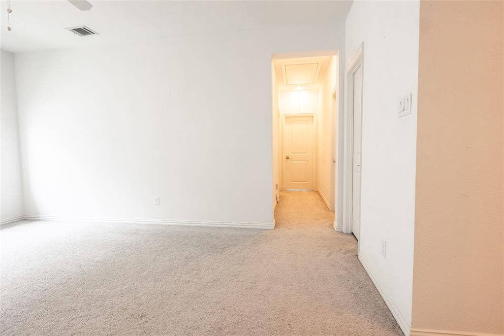 Neutral-toned carpeting, smooth-finish walls, ceiling-mounted light fixture, and interior panel door