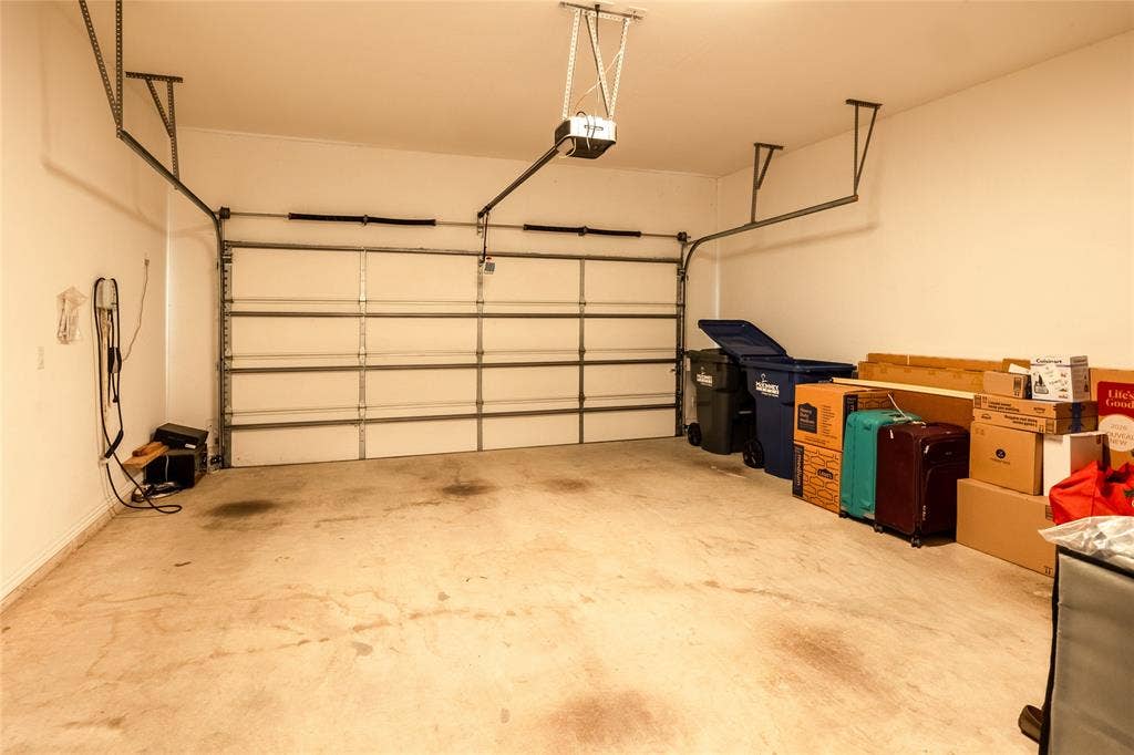 Two-car garage featuring a sectional overhead door, painted drywall, and concrete flooring