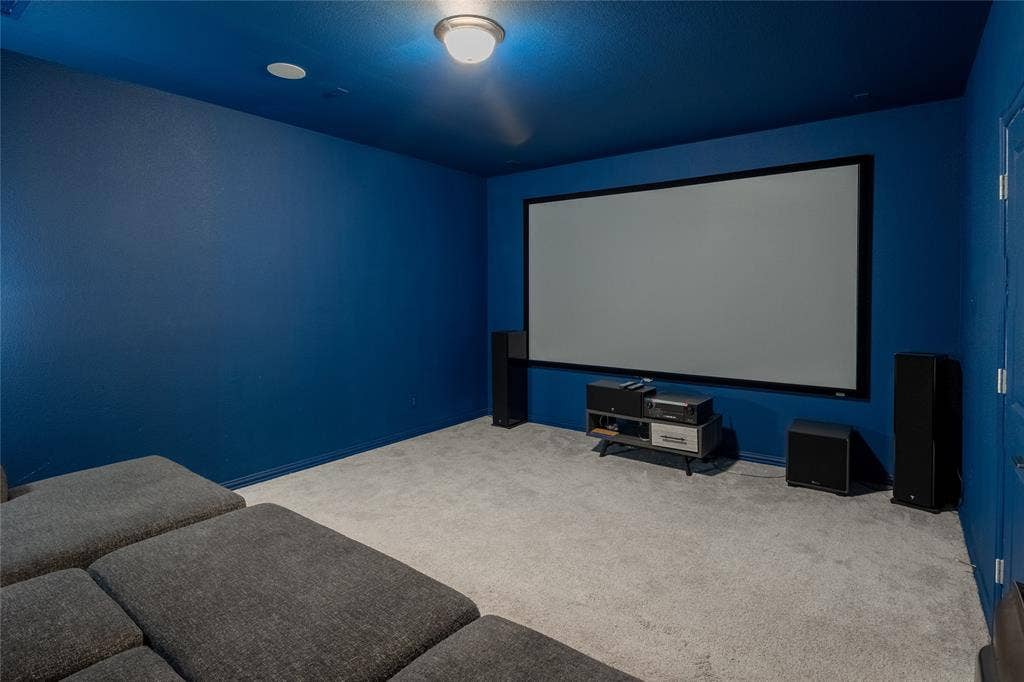 Enclosed media room featuring wall-to-wall carpeting, recessed ceiling lighting, and a large, wall-mounted projection screen