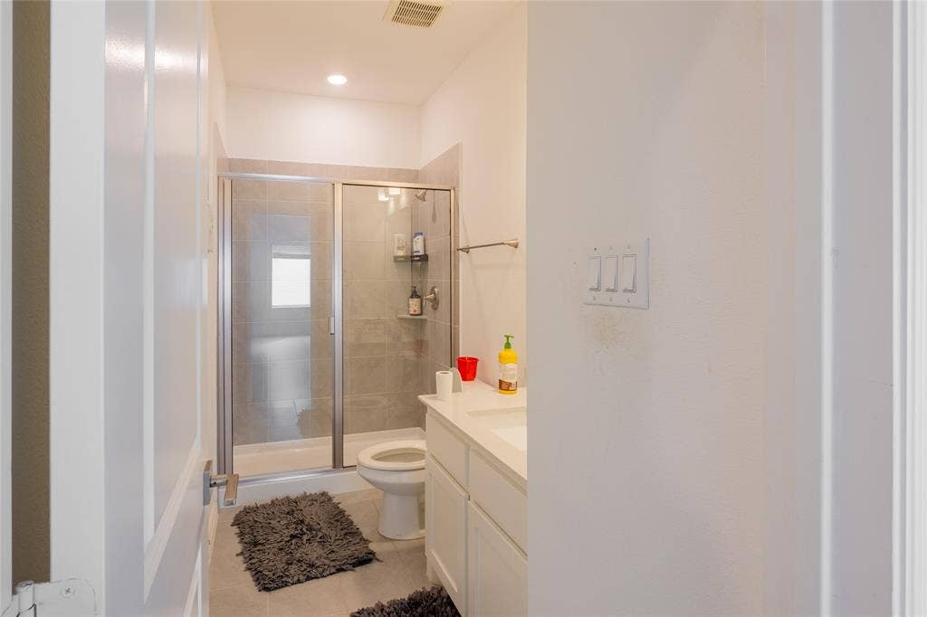 Bathroom featuring a glass-enclosed shower with tiled surround, white vanity cabinetry, integrated countertop sink, and recessed lighting