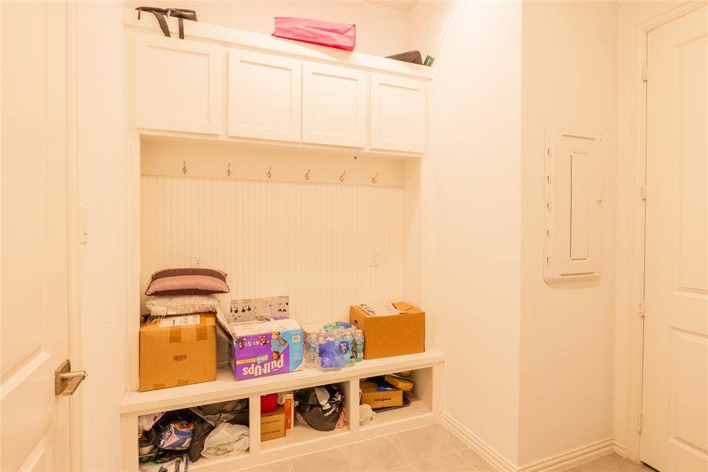 Built-in white storage cabinetry featuring overhead lockers, beadboard paneling with multiple metal coat hooks, and open lower cubbies