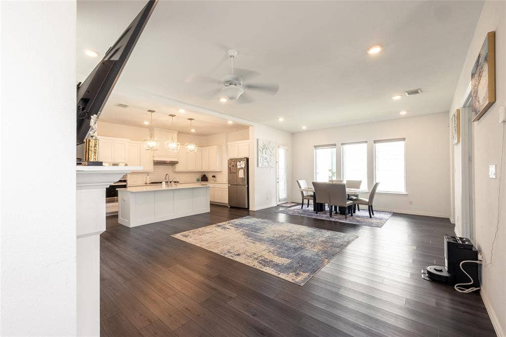 Open-concept interior featuring wood-finish flooring, recessed lighting, and a kitchen equipped with a central island and white cabinetry