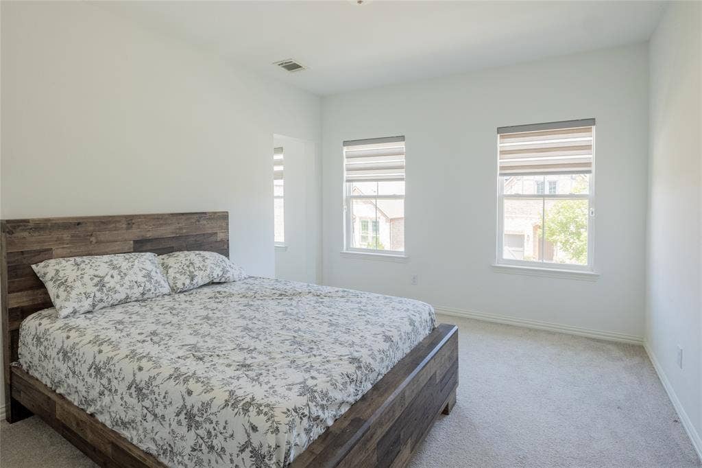Neutral wall finishes, plush carpeting, and two windows with dual-layer privacy blinds