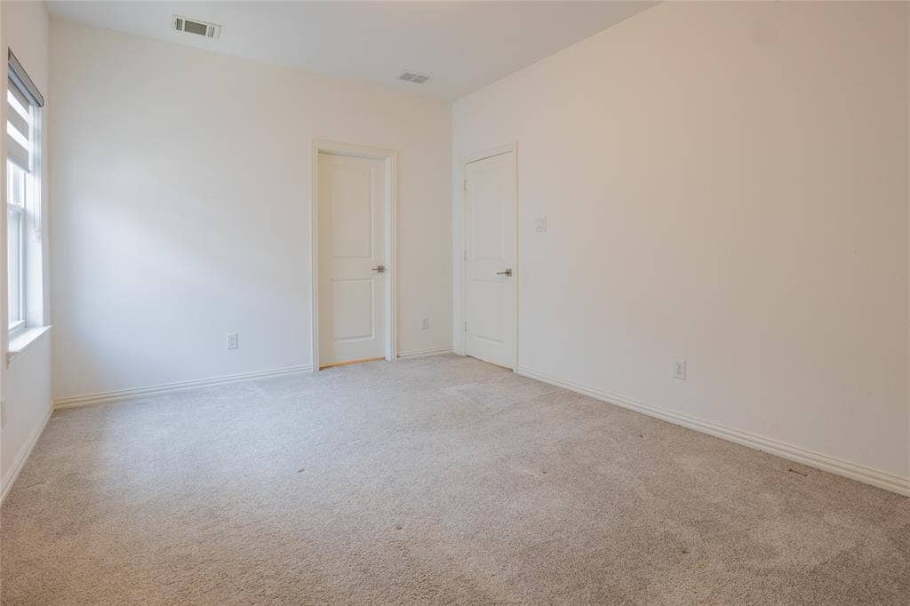Neutral-toned wall-to-wall carpeting, two interior doors with brushed nickel hardware, and a single-hung window with a screen and horizontal window treatment