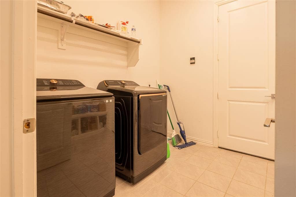 Utility room featuring neutral tile flooring, built-in shelving, and a solid-core interior door