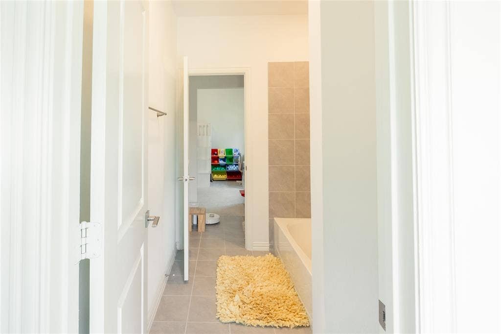 Bathroom featuring large-format neutral tile flooring and a built-in tub surround with matching tiled wall accents