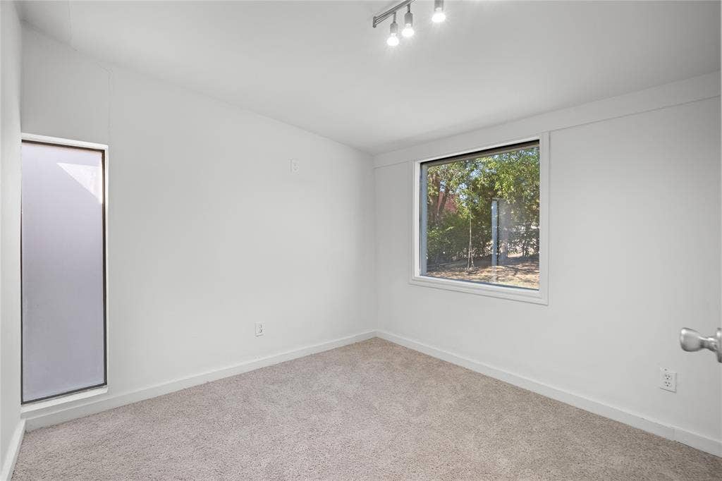 2005 Tisinger Avenue, Dallas, TX 75228 Room featuring neutral carpeting, white walls, multi-directional track lighting, and dual windows