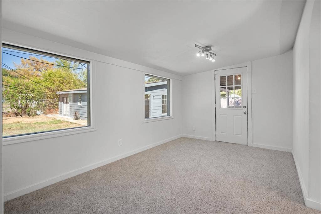 2005 Tisinger Avenue, Dallas, TX 75228 Interior room featuring neutral wall finishes, wall-to-wall carpeting, multiple windows, a multi-light track lighting fixture, and a glass-paneled exterior door