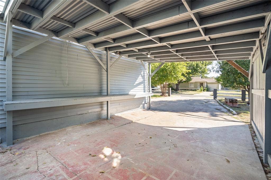2005 Tisinger Avenue, Dallas, TX 75228 Covered carport featuring a structural beam frame, corrugated metal roof, horizontal siding wall, and built-in work surface