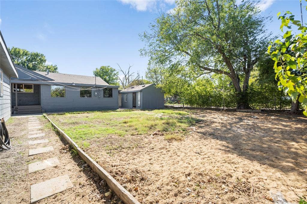 2005 Tisinger Avenue, Dallas, TX 75228 Spacious backyard featuring a detached structure, concrete paver path, mature trees, and perimeter fencing