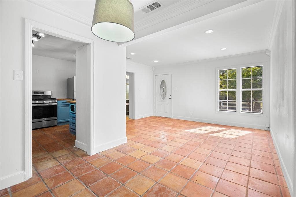 2005 Tisinger Avenue, Dallas, TX 75228 Open interior space featuring terra-cotta tile flooring, recessed lighting, crown molding, and an exterior door with decorative oval glass inlay