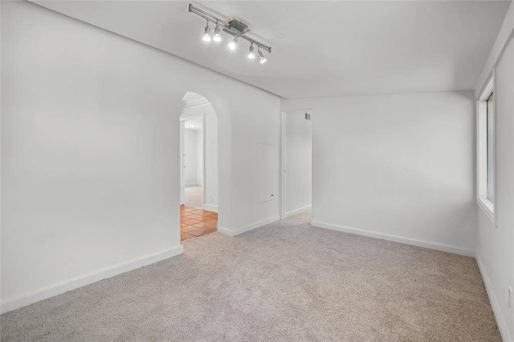 2005 Tisinger Avenue, Dallas, TX 75228 Interior space featuring neutral wall-to-wall carpeting, an arched doorway, and a ceiling-mounted four-light track fixture