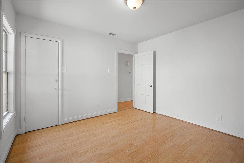 2005 Tisinger Avenue, Dallas, TX 75228 Room featuring wood-finish flooring, white walls, flush-mount ceiling lighting, a solid-panel door, and a multi-pane glass door