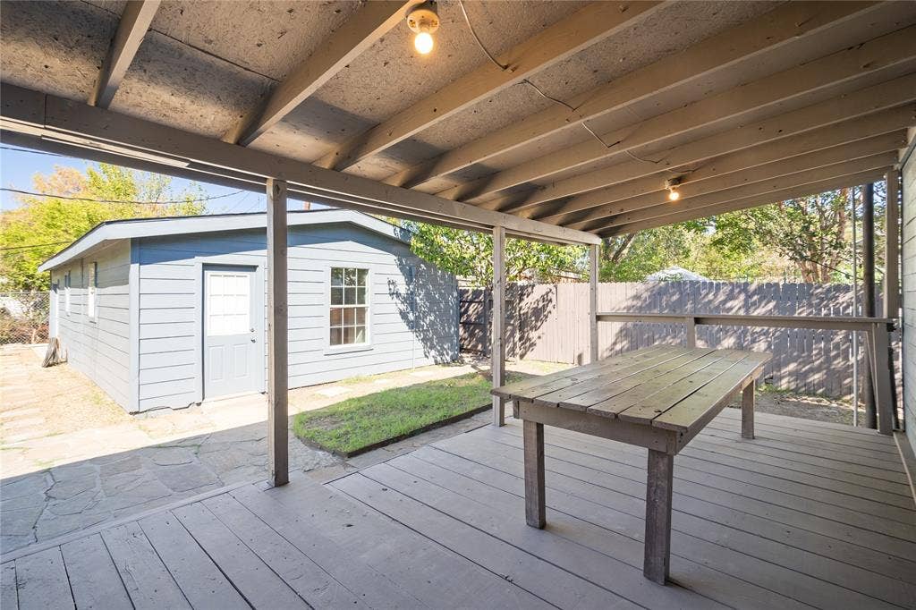2005 Tisinger Avenue, Dallas, TX 75228 Covered deck with painted wood decking, overhead support beams, and exposed rafters, featuring an integrated flagstone patio and a detached structure with horizontal siding