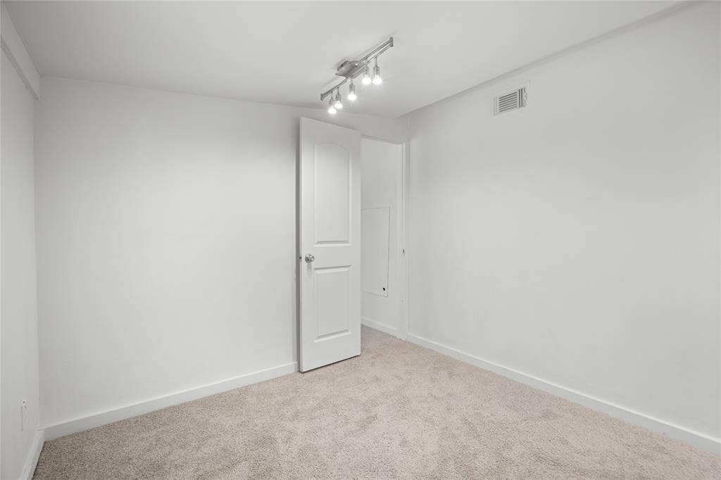 2005 Tisinger Avenue, Dallas, TX 75228 Room featuring neutral carpeting, a white paneled door, and a multi-directional track lighting fixture