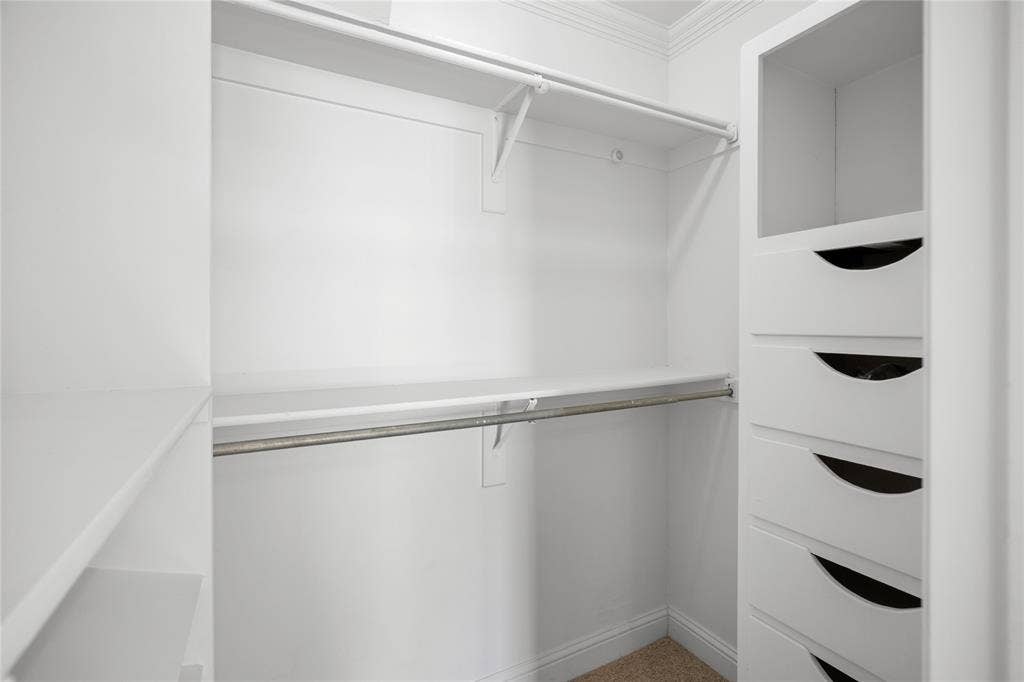 2005 Tisinger Avenue, Dallas, TX 75228 Walk-in storage space featuring built-in white cabinetry, integrated drawers with recessed pulls, tiered shelving, and metal hanging rods