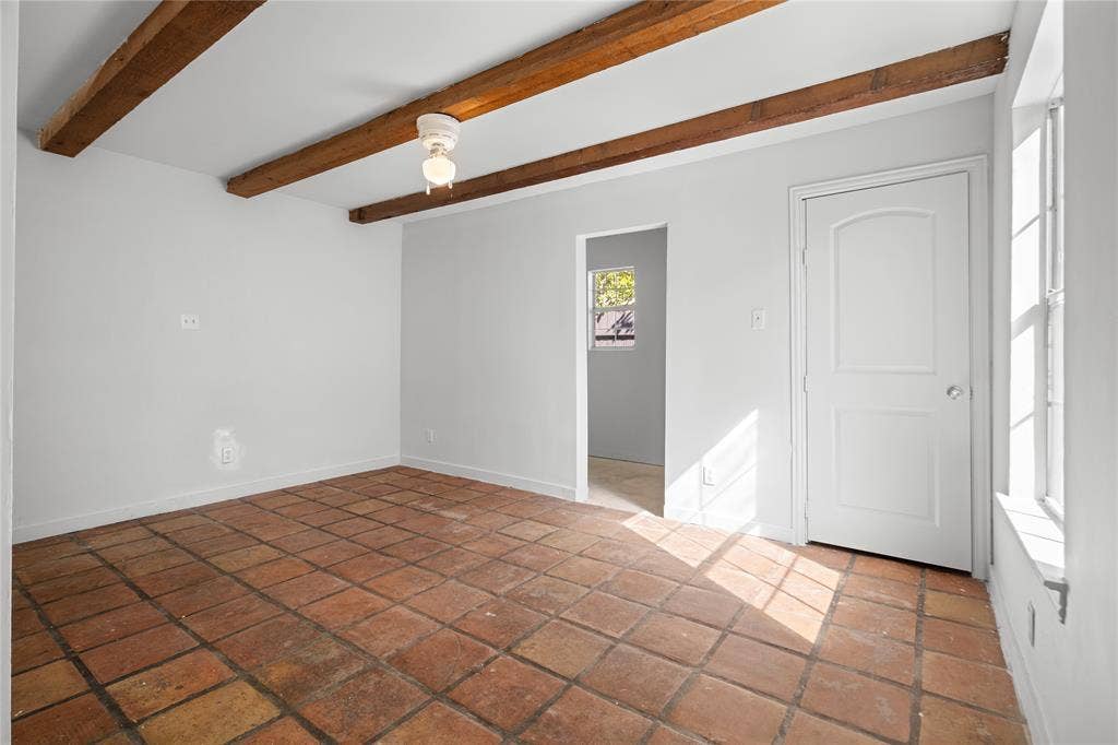 2005 Tisinger Avenue, Dallas, TX 75228 Room featuring exposed wooden ceiling beams, terracotta tile flooring, a multi-pane window, and an arched-panel interior door