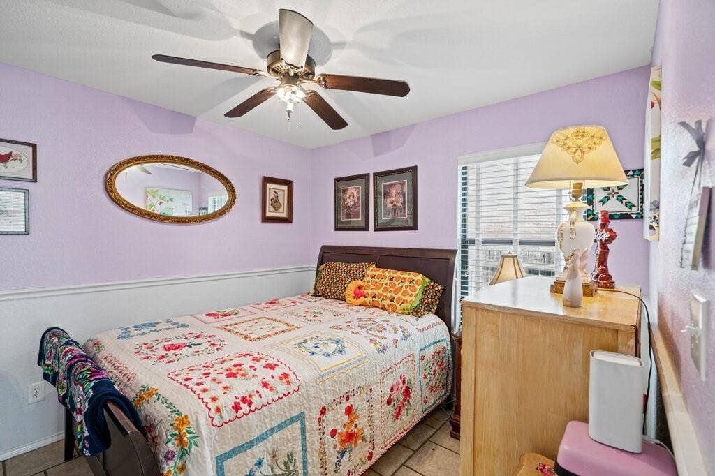 Room featuring tile flooring, ceiling fan with integrated lighting, window with horizontal blinds, and chair rail molding
