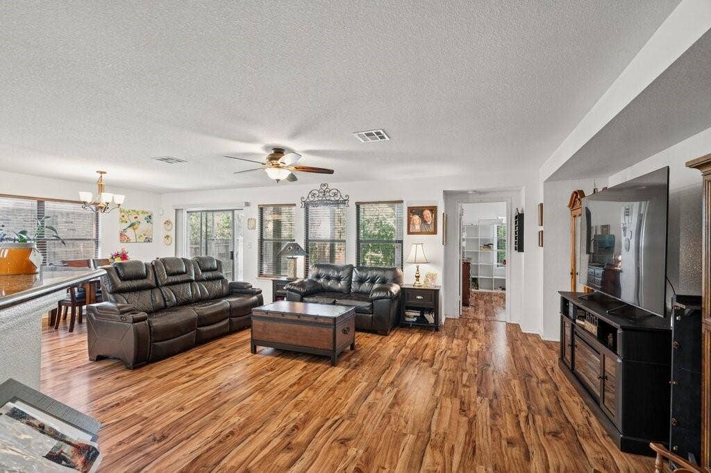 Living area featuring wood-finish flooring, recessed lighting, ceiling fan with light kit, and large windows
