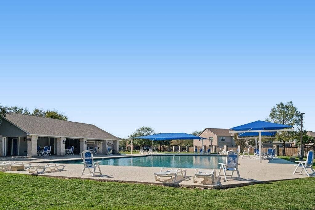 Swimming pool featuring a concrete deck, built-in shade structures, and an attached covered pavilion