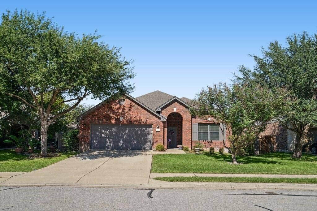 Single-story brick exterior featuring a multi-gabled roofline, an arched entryway, and an attached two-car garage