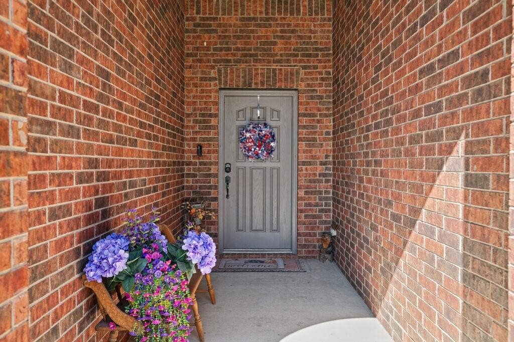 Covered entryway featuring multi-tonal brick masonry and a paneled grey entry door
