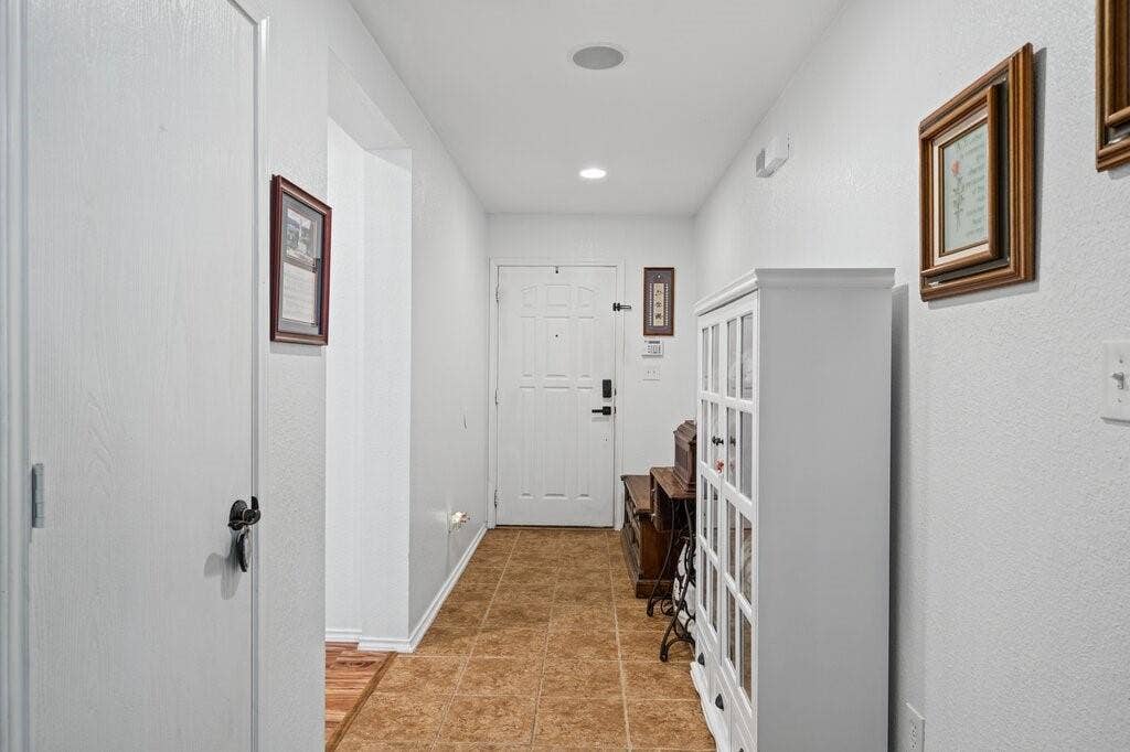 Entryway featuring neutral-toned tile flooring, recessed ceiling lighting, and a paneled entry door with matte black hardware