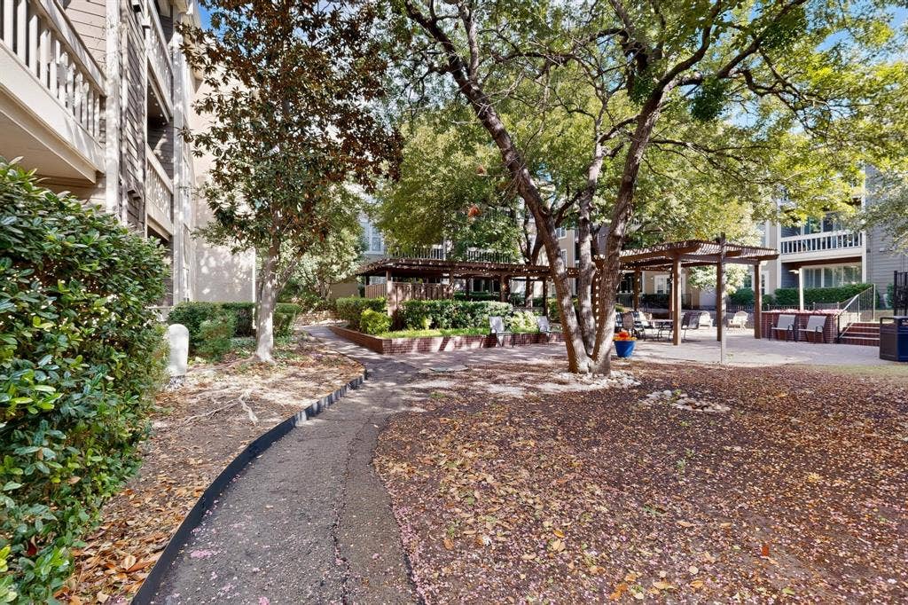 Explore the park-like setting of the common areas featuring wooden pergolas, mature trees, and landscaping.