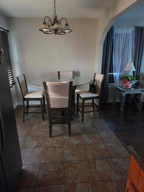Textured tile flooring, arched wall detailing, and a multi-light metal chandelier