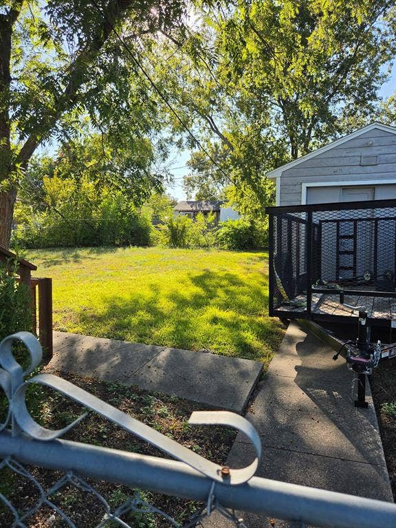 Expansive backyard featuring a level lawn, concrete walkway, and mature trees