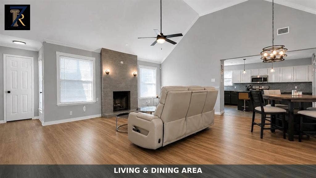 Vaulted ceilings, wood-finish flooring, floor-to-ceiling fireplace with stone-style surround, and recessed lighting