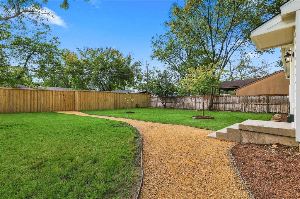 11624 Rupley Lane, Dallas, TX 75218 Private backyard featuring a manicured lawn, gravel pathway, wood privacy fencing, and concrete steps