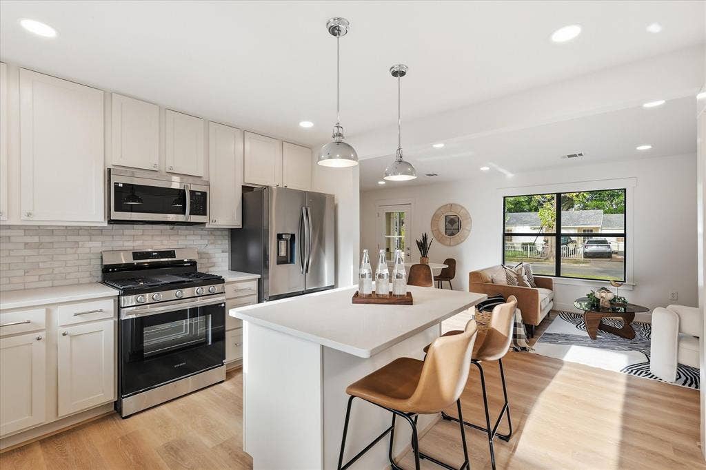 11624 Rupley Lane, Dallas, TX 75218 Kitchen featuring shaker-style cabinetry, a central island with a quartz countertop, stainless steel appliances, subway tile backsplash, and recessed lighting