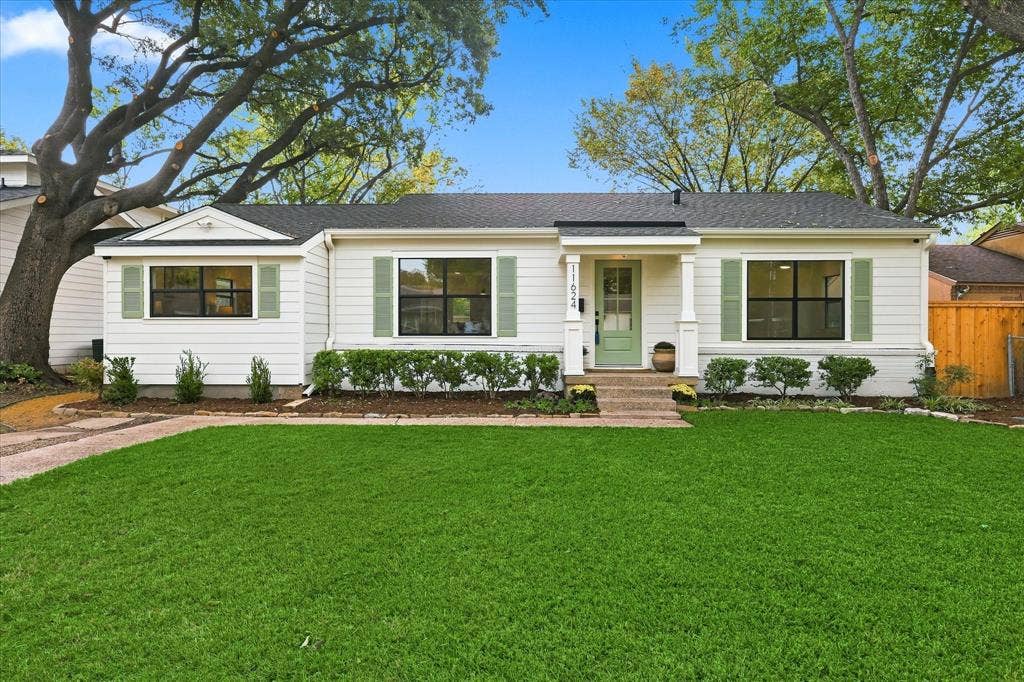 11624 Rupley Lane, Dallas, TX 75218 Single-story exterior featuring white horizontal siding, sage green shutters, a covered front entryway with square columns, and a mature shade tree