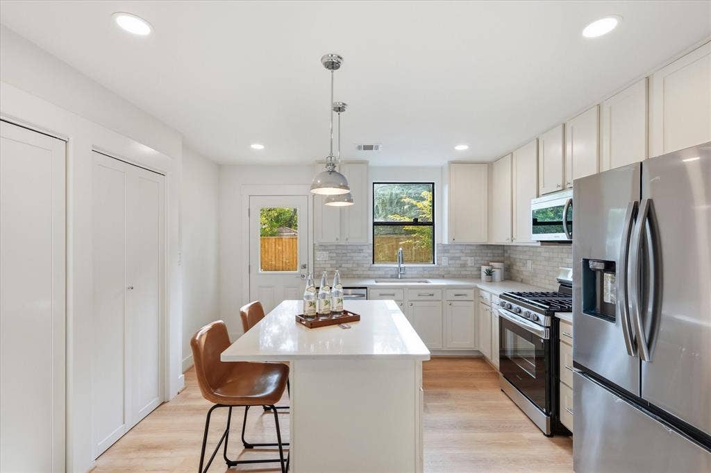 11624 Rupley Lane, Dallas, TX 75218 Kitchen featuring white shaker-style cabinetry, quartz countertops, a central island, recessed lighting, and stainless steel appliances