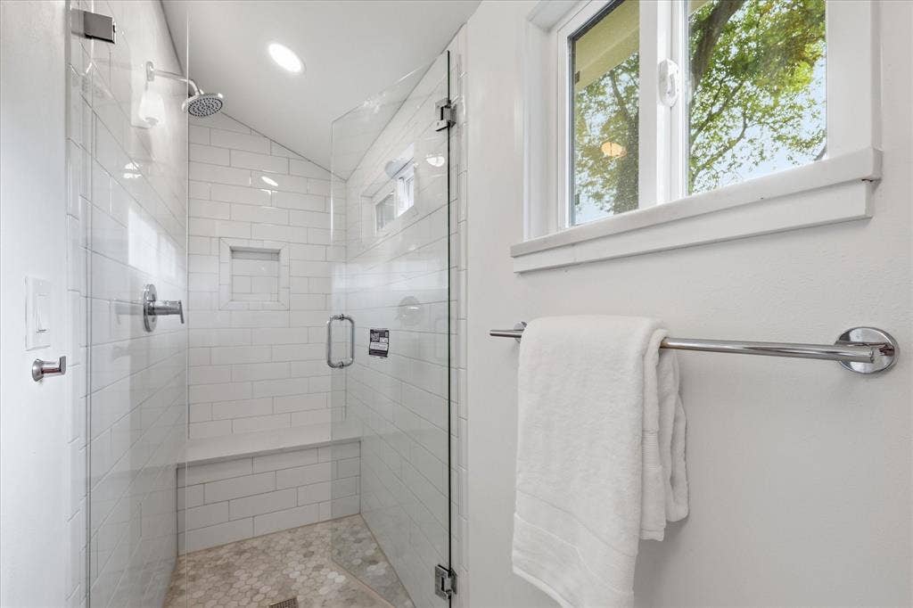 11624 Rupley Lane, Dallas, TX 75218 Walk-in shower featuring subway tile surround, built-in bench, glass enclosure, recessed wall niche, and natural stone pebble flooring