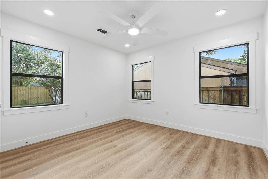 11624 Rupley Lane, Dallas, TX 75218 Interior room featuring wood-finish flooring, white walls, three windows with black frames and white trim, recessed lighting, and a white ceiling fan