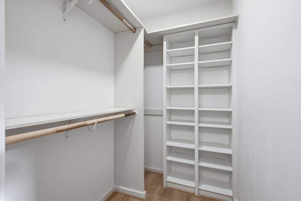 11624 Rupley Lane, Dallas, TX 75218 Walk-in closet featuring white built-in shelving, wooden garment rods, and wood-finish flooring